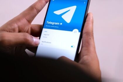 Close-up of hands holding a smartphone with the Telegram app open on the screen.